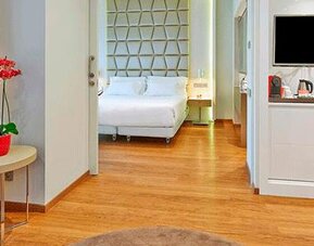 Spacious suite featuring wood flooring, a separate sleeping area, television and coffee station at NH Collection Barcelona Pódium.