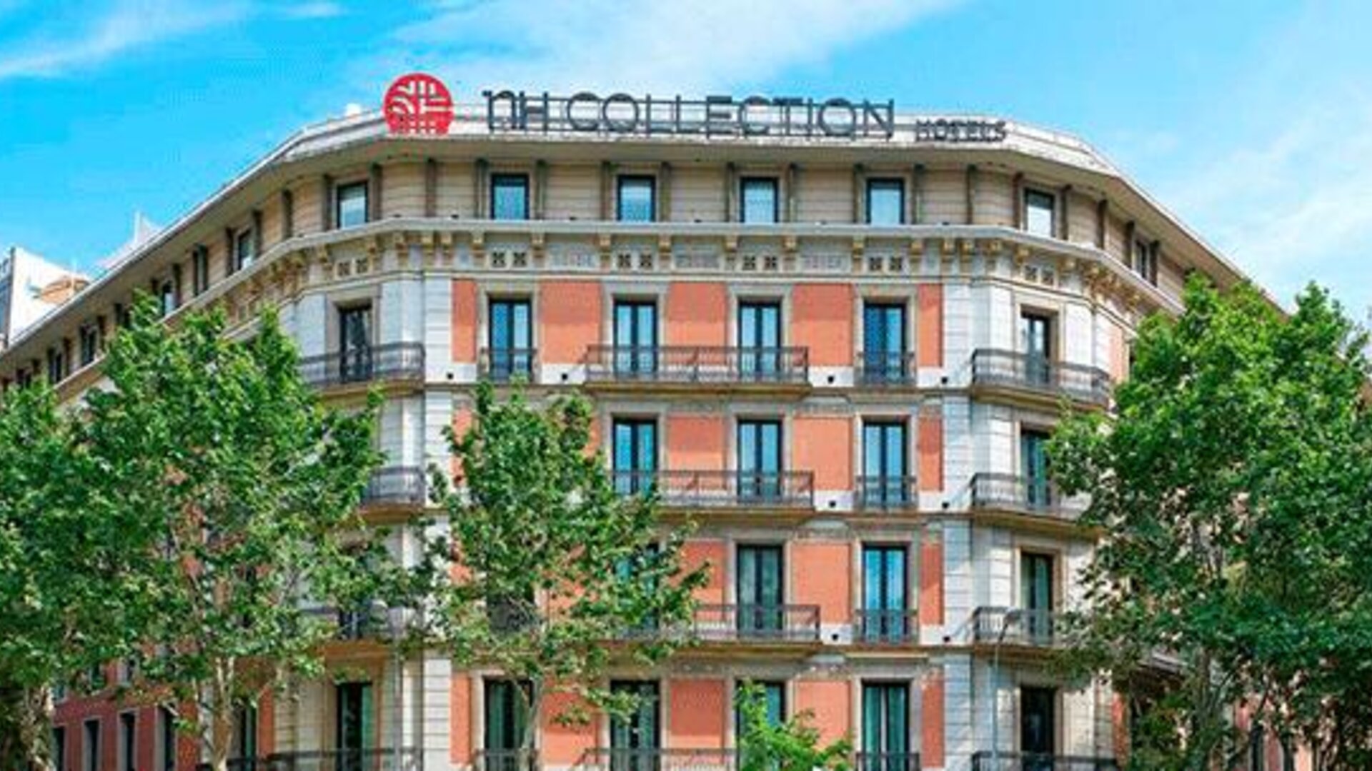 Exterior view of the historic building with balconies and surrounding trees at NH Collection Barcelona Pódium.