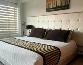 Spacious guest room featuring a king bed, seating area, polished wood flooring and large windows at Hotel Airport Travel.