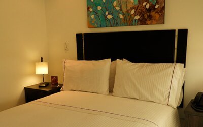 Cozy guest room featuring a double bed, bedside tables, floral arrangement and decorative wall art at Hotel Airport Travel.