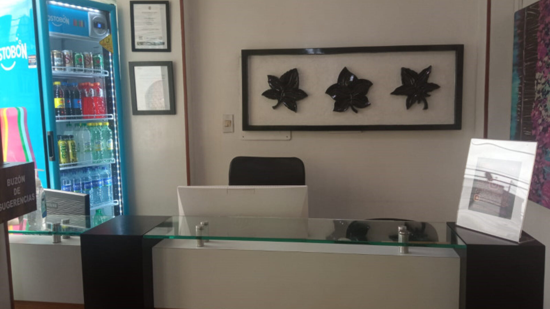Front desk area featuring a glass-topped reception counter, decorative wall art and beverage vending machine at Hotel Airport Travel.