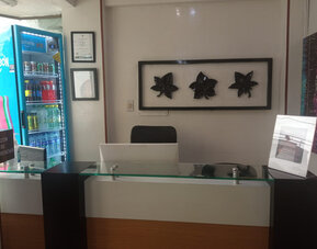 Front desk area featuring a glass-topped reception counter, decorative wall art and beverage vending machine at Hotel Airport Travel.