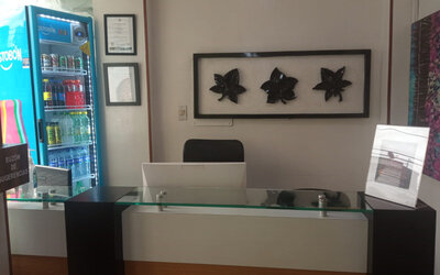 Front desk area featuring a glass-topped reception counter, decorative wall art and beverage vending machine at Hotel Airport Travel.