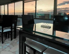 Rooftop dining area featuring glass-top tables, black chairs and panoramic city views at Hotel Airport Travel.
