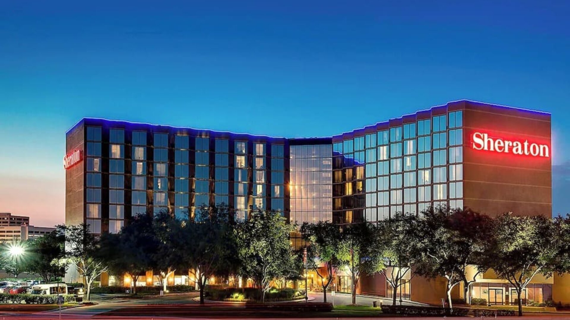 Modern hotel exterior featuring illuminated signage, contemporary architecture and landscaped grounds at Sheraton Houston Brookhollow Hotel.