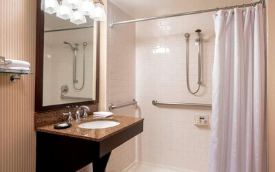 Accessible bathroom featuring a roll-in shower, safety grab bars and a granite vanity at Sheraton Houston Brookhollow Hotel.