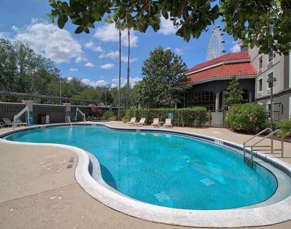 Outdoor swimming pool featuring a curved design, surrounding sun loungers and landscaped grounds at La Quinta Inn & Suites By Wyndham Orlando I Drive/Conv Ctr.