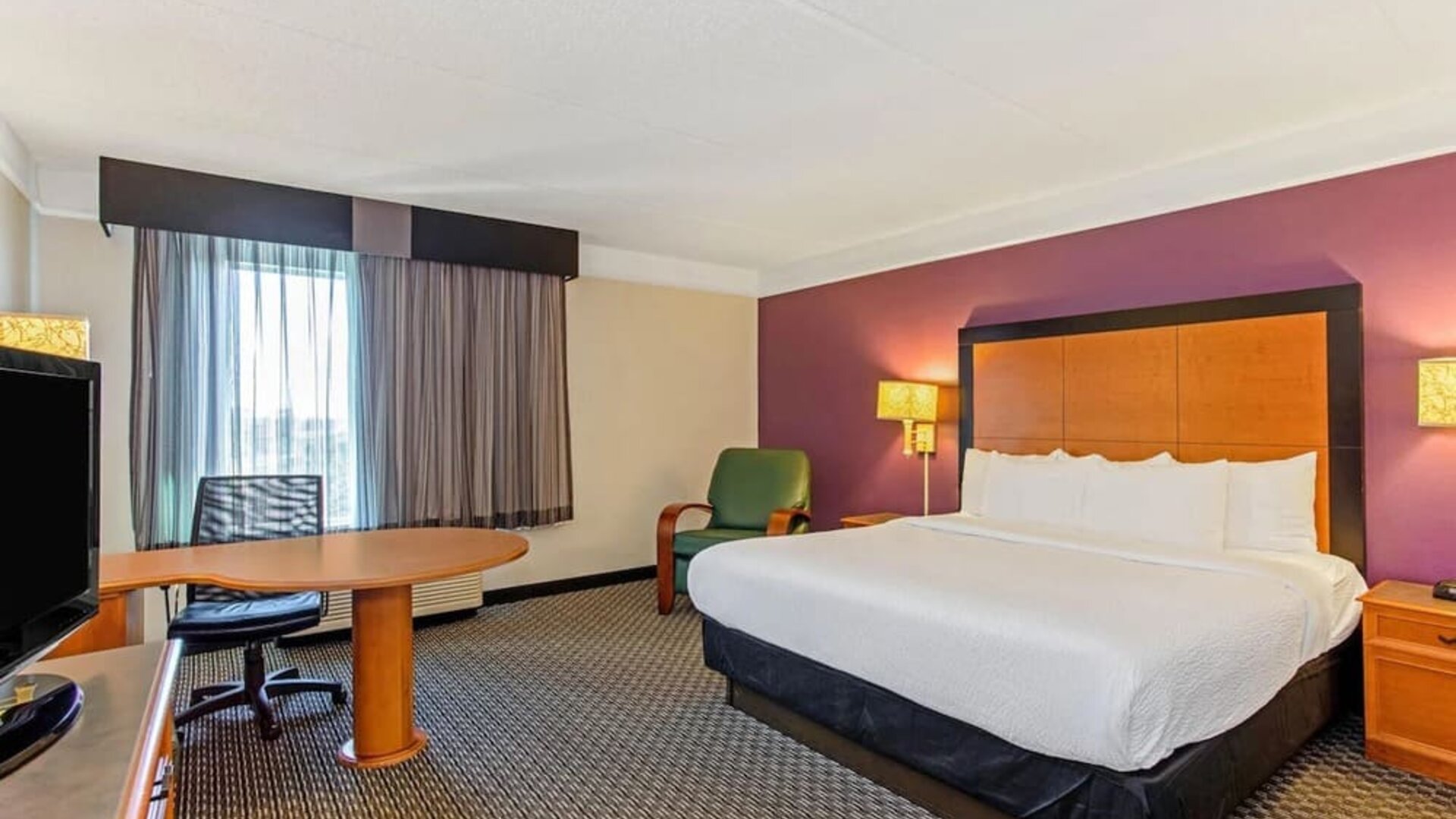 Contemporary guest room featuring a king-size bed, a spacious work area and modern furnishings at La Quinta Inn & Suites By Wyndham Orlando I Drive/Conv Ctr.
