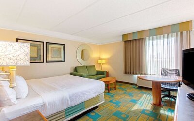 Bright guest room featuring a king-size bed, a comfortable seating area and abundant natural light at La Quinta Inn & Suites By Wyndham Orlando I Drive/Conv Ctr.