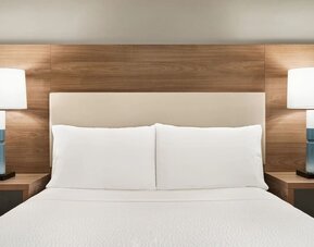 Comfortable guest room featuring a plush bed, wood-accented furnishings and bedside lighting at Candlewood Suites Meridian.