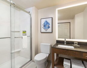 Modern bathroom featuring a spacious vanity, a glass-enclosed shower and neatly arranged towels at Candlewood Suites Meridian.