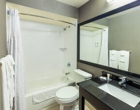 Modern bathroom featuring a tub and shower combination, a granite vanity and a large framed mirror at Comfort Inn Truro.