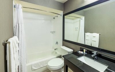 Modern bathroom featuring a tub and shower combination, a granite vanity and a large framed mirror at Comfort Inn Truro.