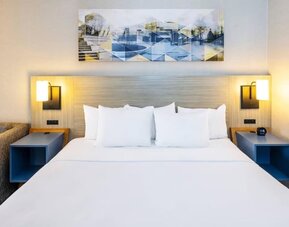 Contemporary guest room featuring a king-size bed, modern lighting and artwork above the headboard at Comfort Inn Truro.
