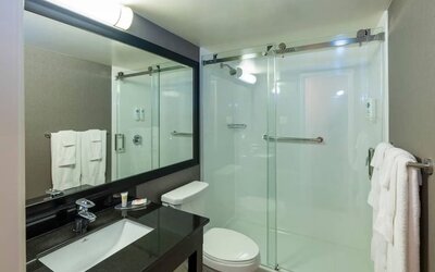 Updated bathroom featuring a walk-in glass shower, a granite vanity and contemporary fixtures at Comfort Inn Truro.