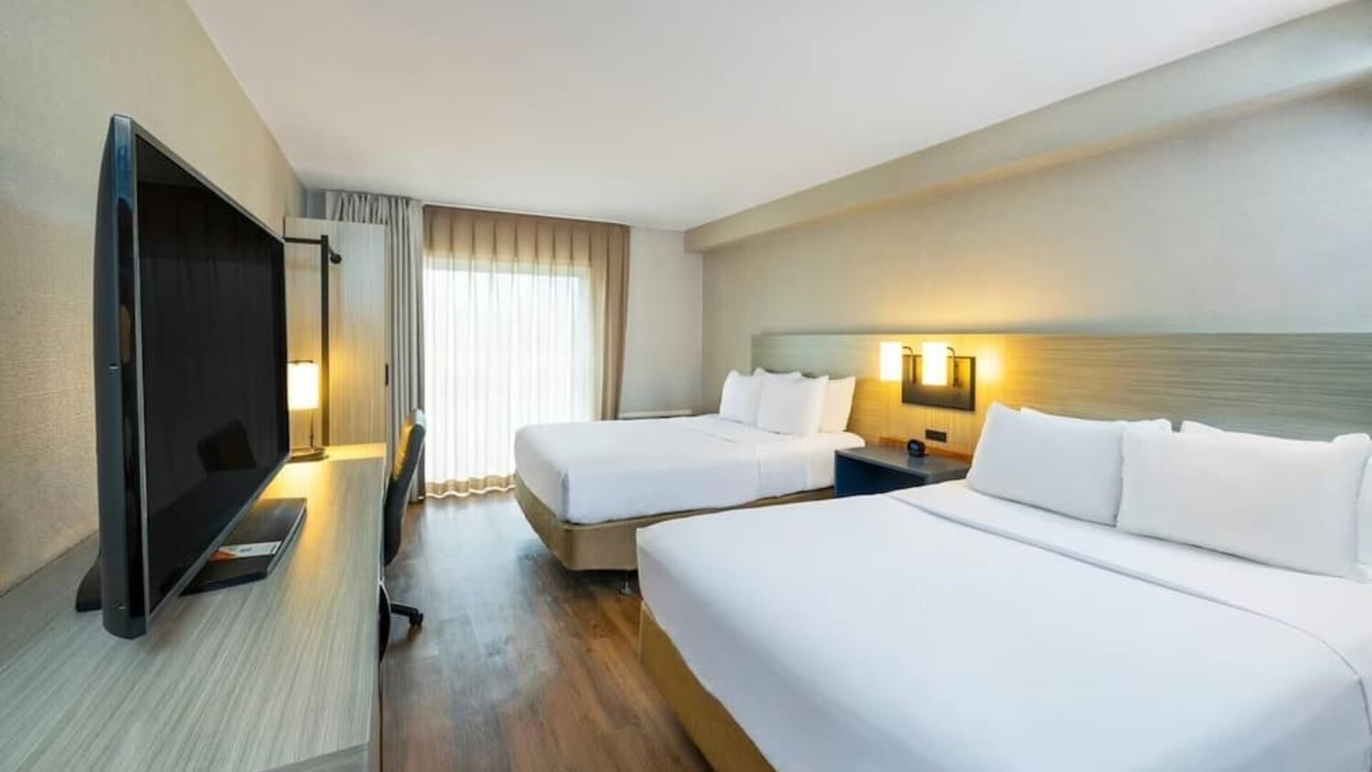 Spacious guest room featuring two beds, a large television and a contemporary design suitable for families or groups at Comfort Inn Truro.