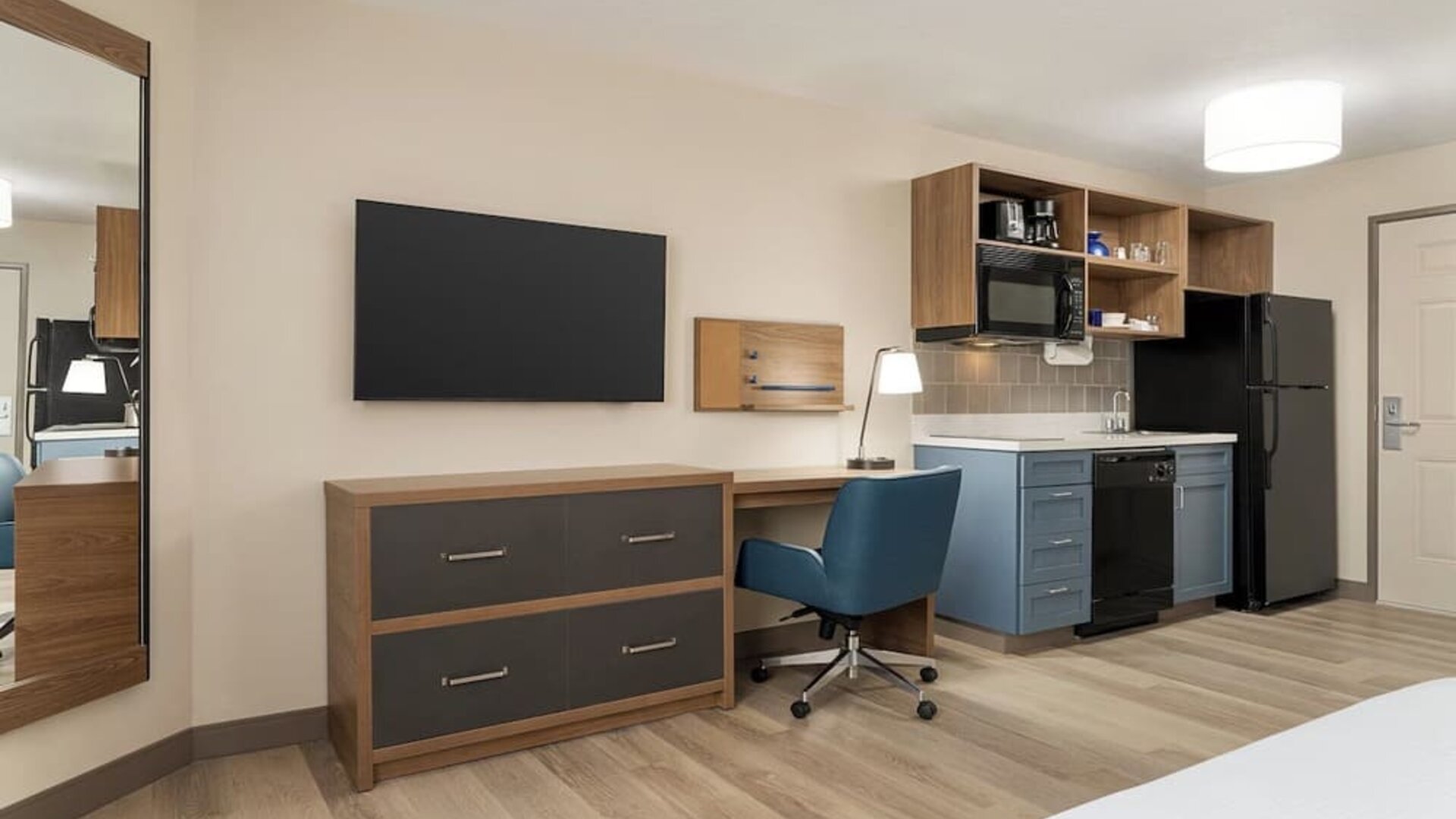 In-room workspace and kitchenette featuring a full-size refrigerator, cooktop, microwave and dedicated desk area at Candlewood Suites Boise.