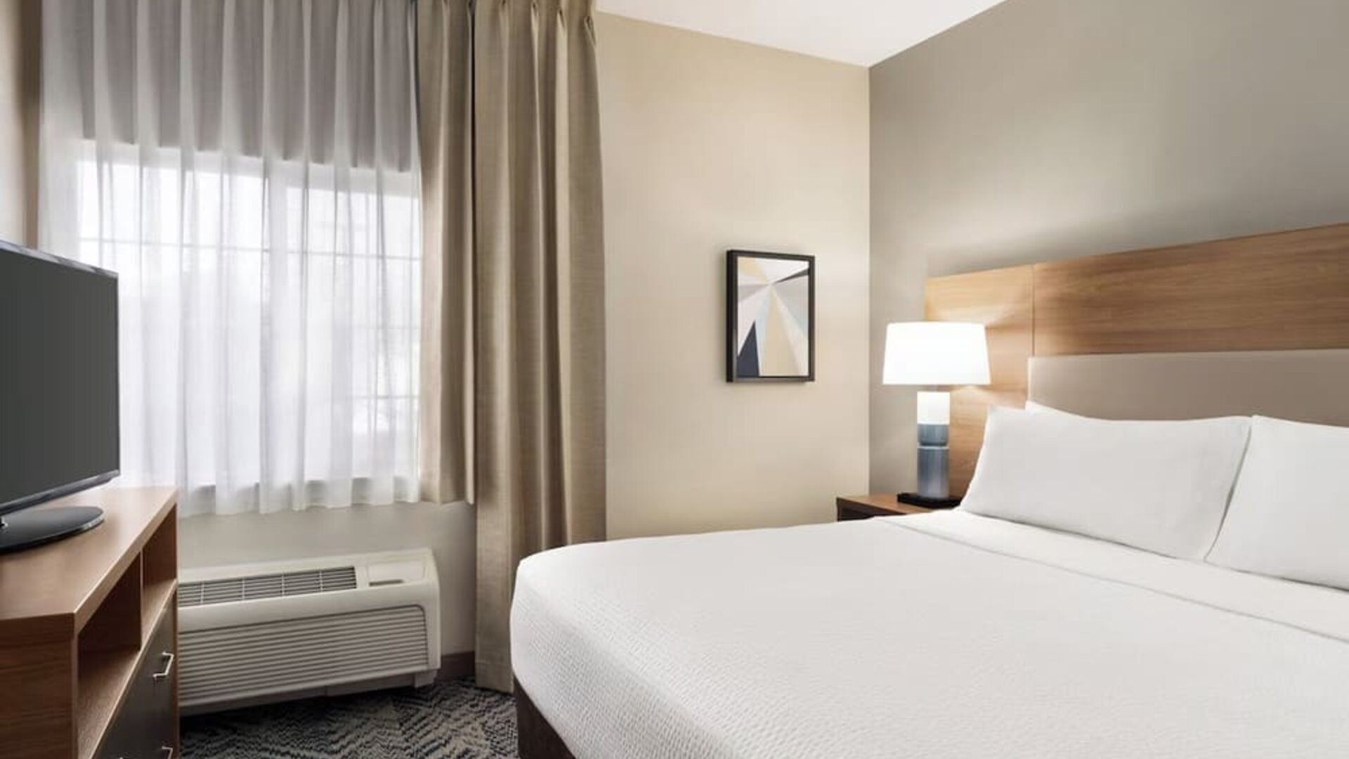 Guest room featuring a queen-size bed, natural light and contemporary furnishings designed for comfort at Candlewood Suites Boise.