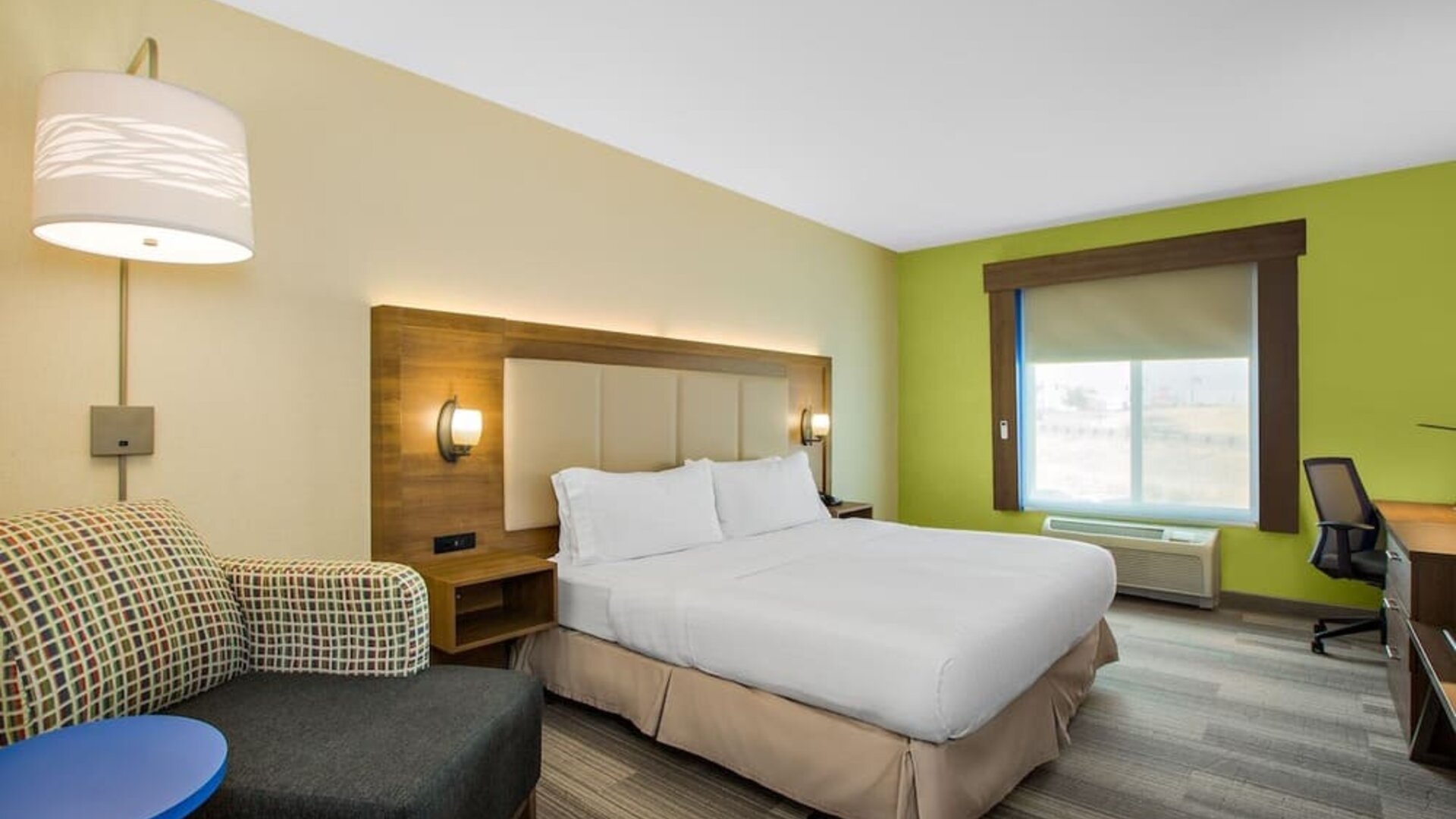 Guest room featuring a king-size bed, a comfortable seating area and a dedicated workspace with natural light at Holiday Inn Express & Suites Ontario.