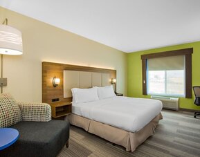 Guest room featuring a king-size bed, a comfortable seating area and a dedicated workspace with natural light at Holiday Inn Express & Suites Ontario.