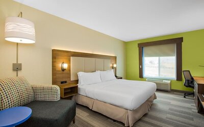 Guest room featuring a king-size bed, a comfortable seating area and a dedicated workspace with natural light at Holiday Inn Express & Suites Ontario.