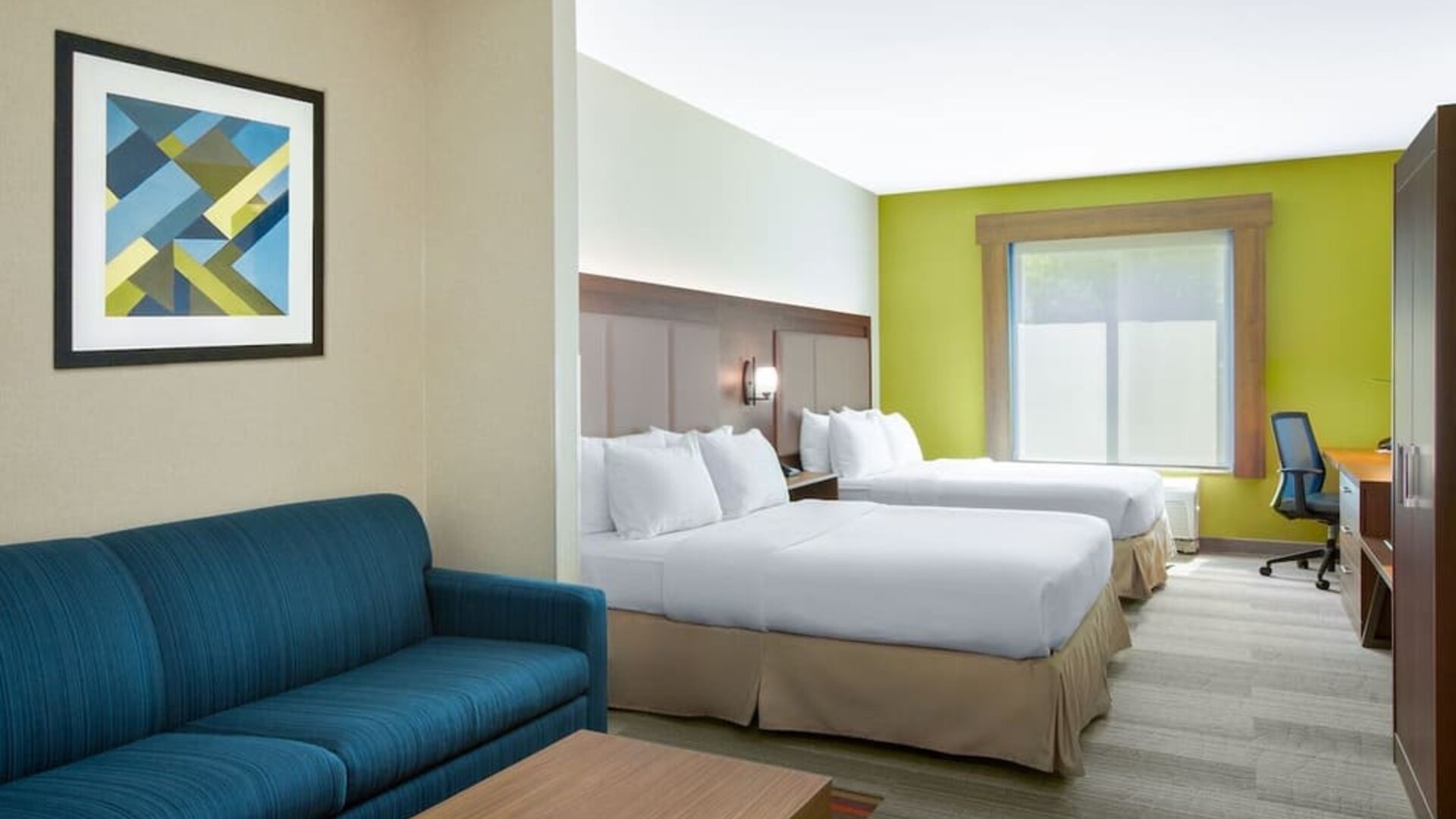 Guest room featuring two beds, a sofa, a work desk and modern décor designed for comfort at Holiday Inn Express & Suites Ontario.