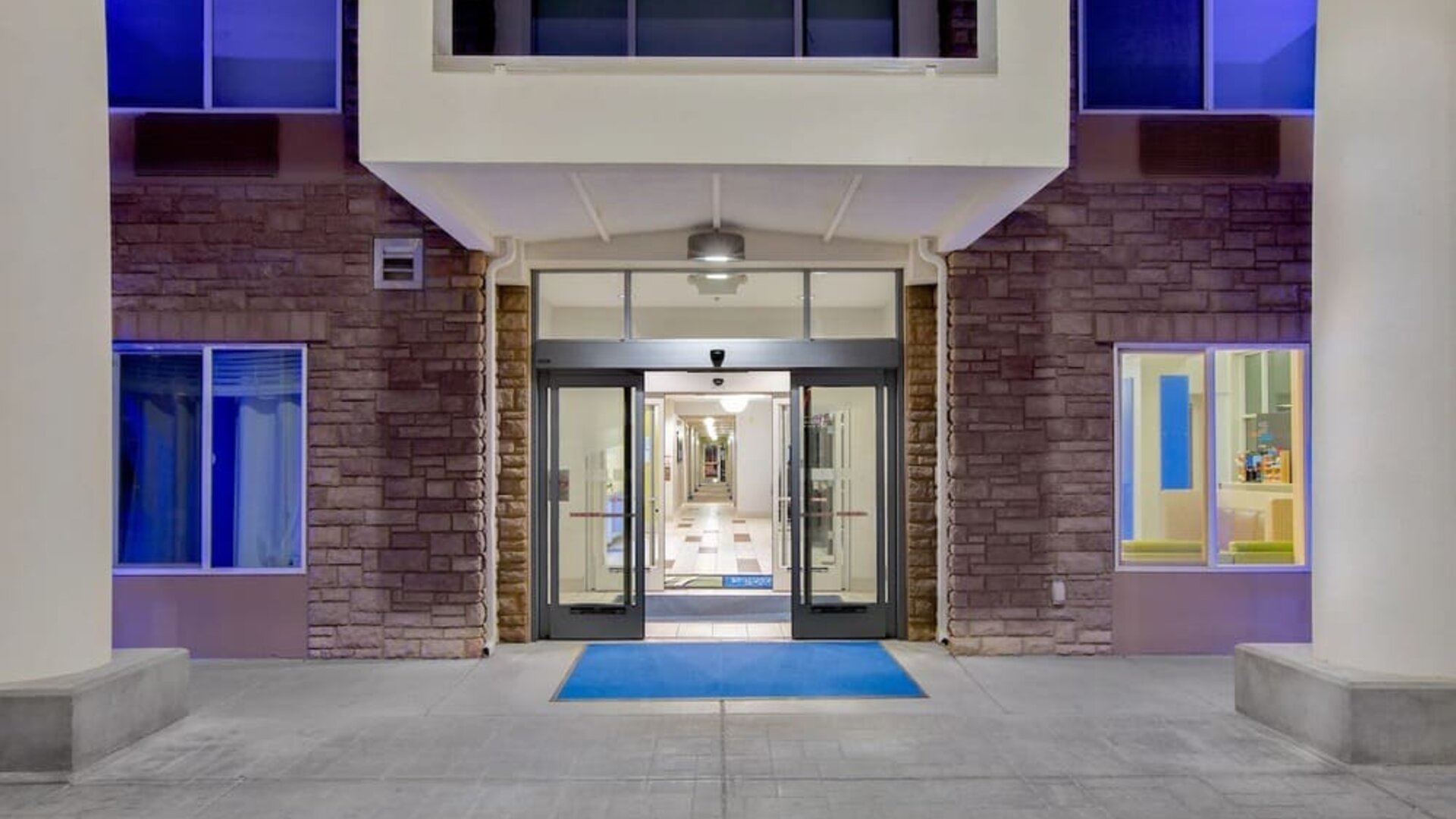 Hotel entrance featuring automatic sliding doors, covered access and contemporary exterior design at Holiday Inn Express & Suites Ontario.