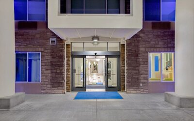 Hotel entrance featuring automatic sliding doors, covered access and contemporary exterior design at Holiday Inn Express & Suites Ontario.