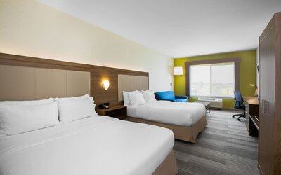 Guest room featuring two beds, a comfortable sofa, a dedicated workspace and modern amenities at Holiday Inn Express & Suites Ontario.