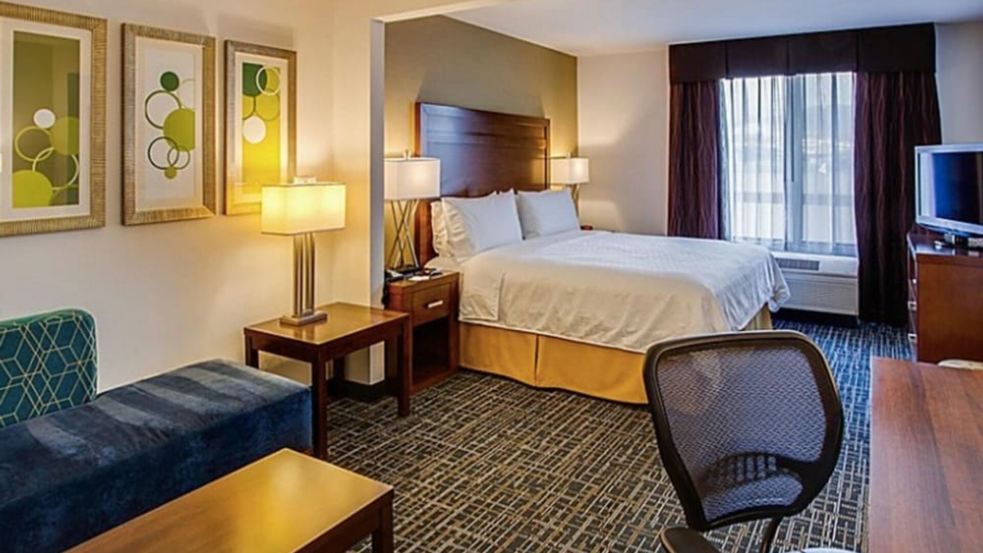 Spacious guest room featuring a king-size bed, a comfortable seating area, a work desk and contemporary furnishings at Holiday Inn Express SFO Airport North.