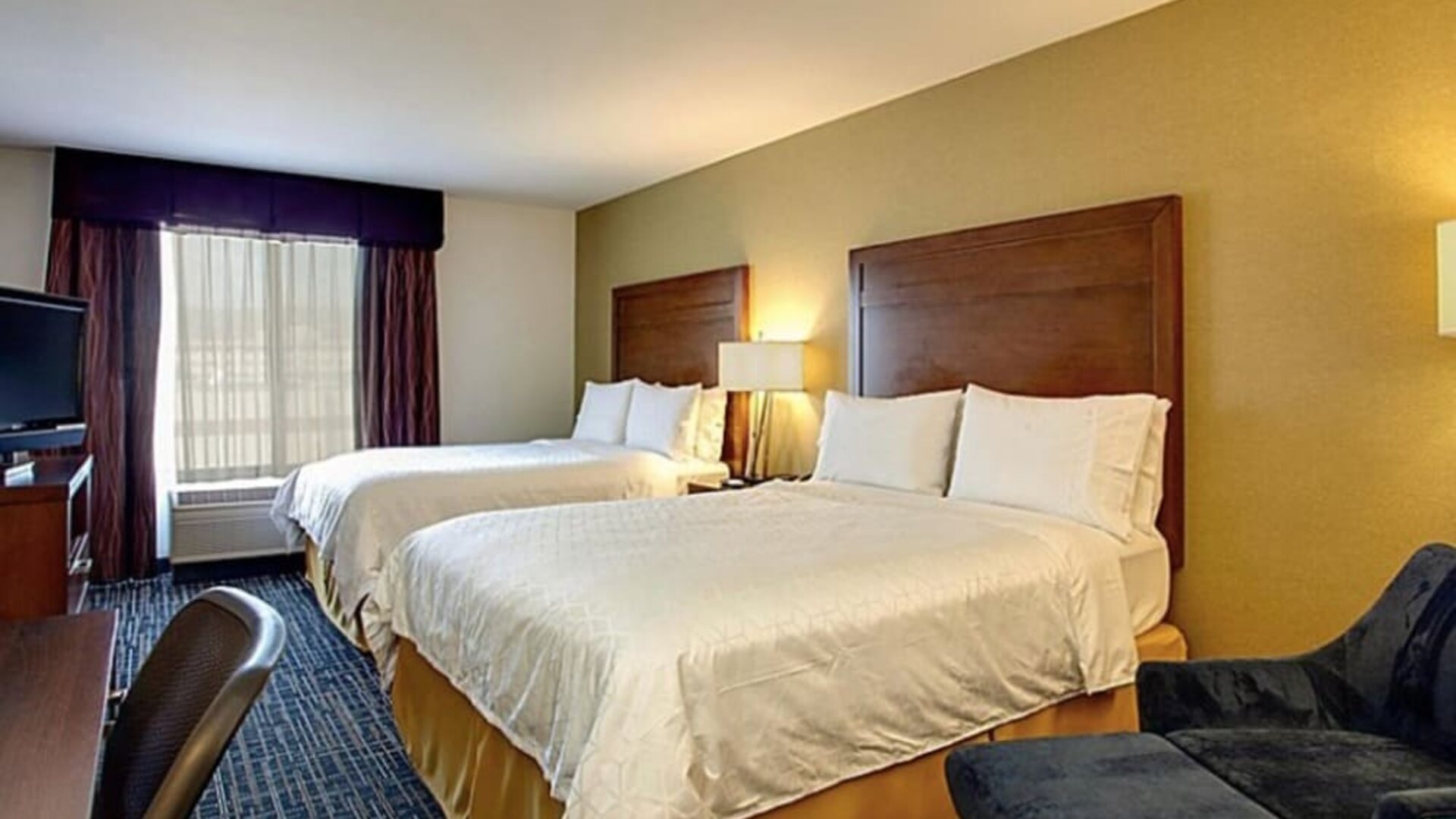 Guest room featuring two beds, a comfortable seating area and modern amenities designed for relaxation at Holiday Inn Express SFO Airport North.