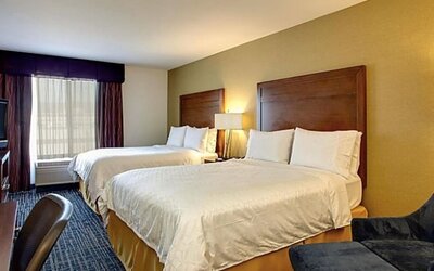 Guest room featuring two beds, a comfortable seating area and modern amenities designed for relaxation at Holiday Inn Express SFO Airport North.