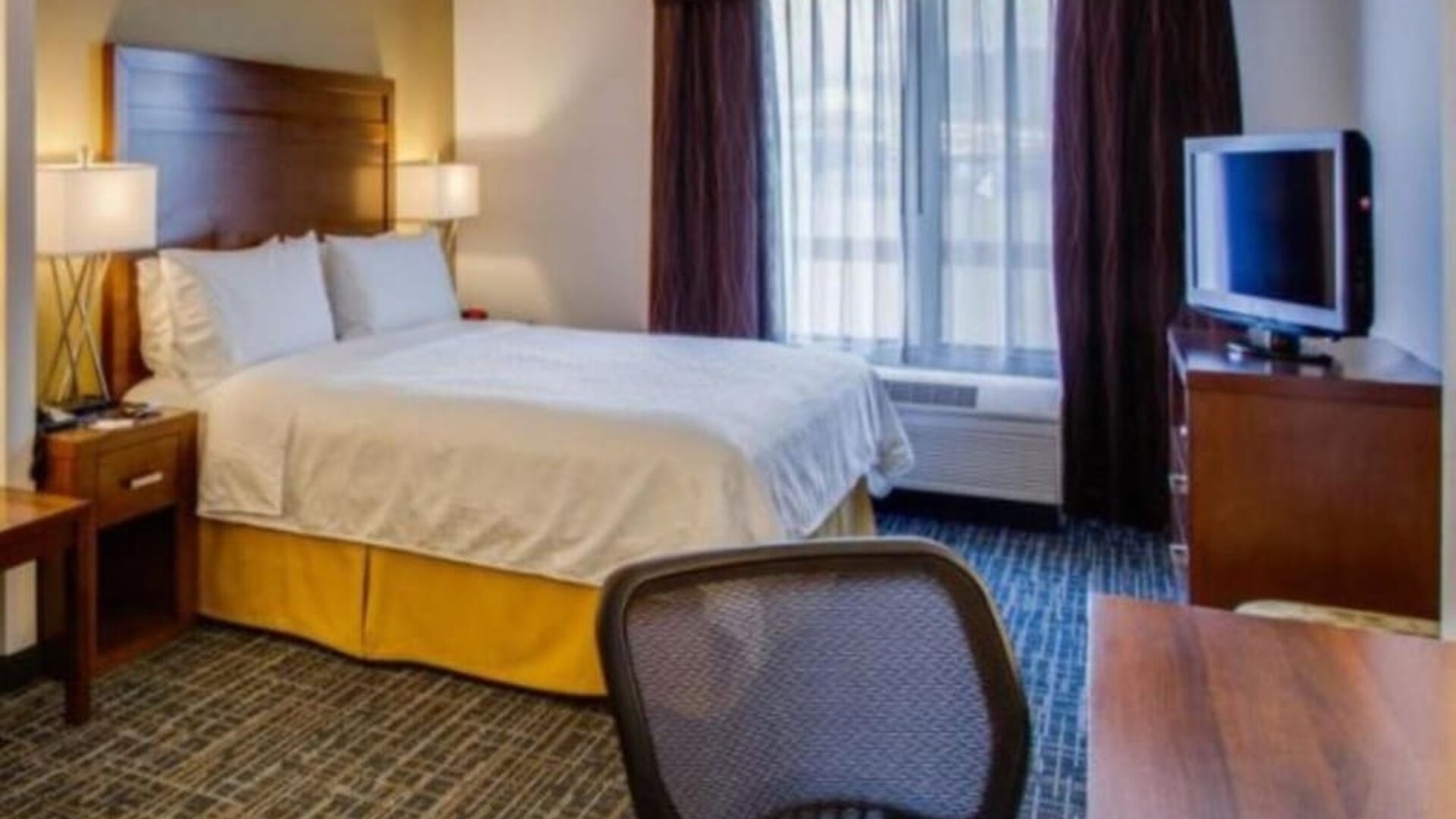 Guest room featuring a king-size bed, a dedicated workspace, a flat-screen television and natural light at Holiday Inn Express SFO Airport North.