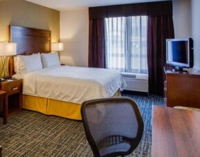 Guest room featuring a king-size bed, a dedicated workspace, a flat-screen television and natural light at Holiday Inn Express SFO Airport North.