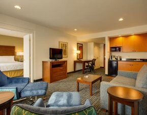 One-bedroom suite featuring a separate bedroom, a living area, a kitchenette and comfortable seating at Holiday Inn Express SFO Airport North.