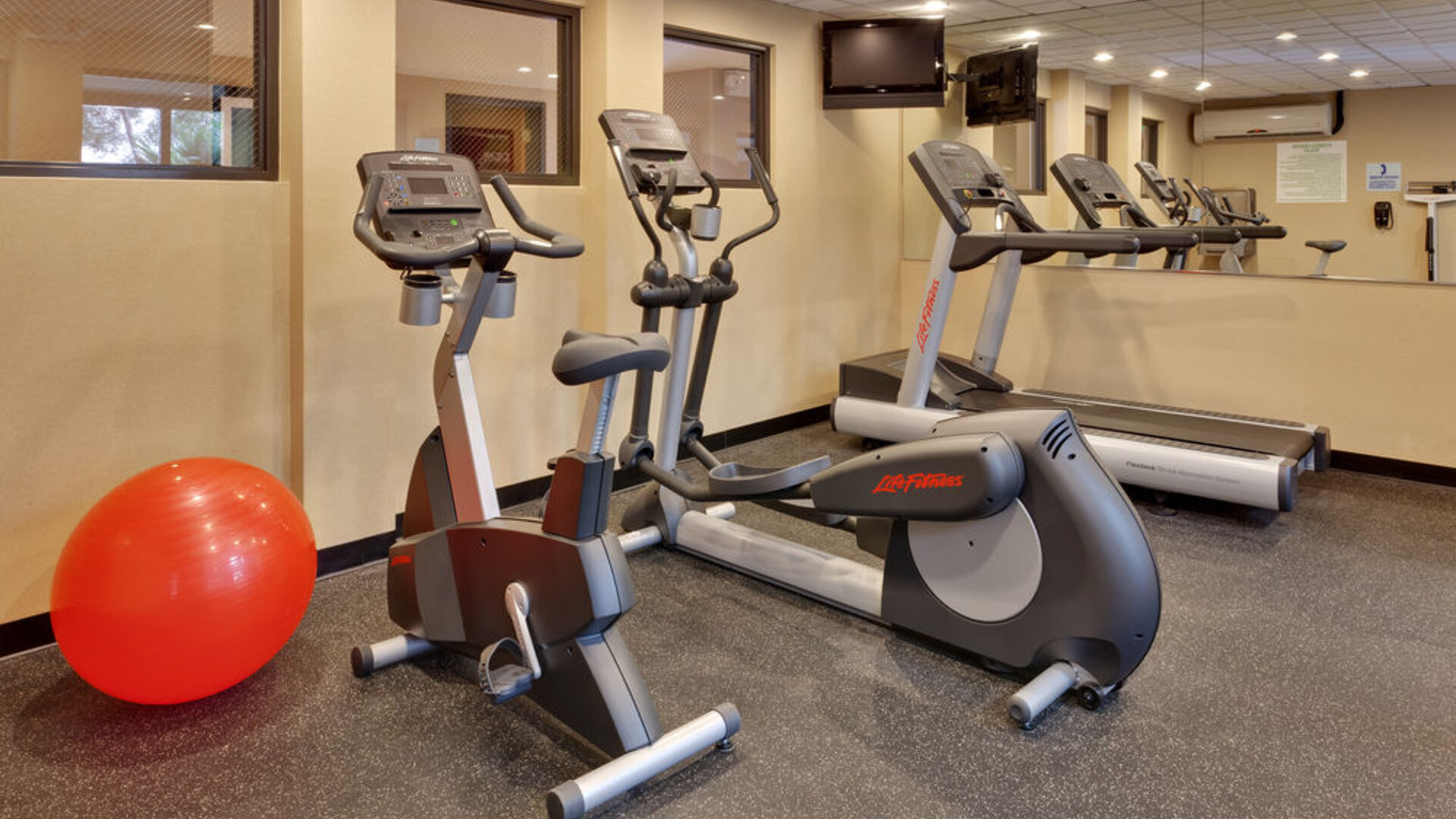 Fitness center featuring cardio equipment, mirrored walls and space for stretching and exercise at Holiday Inn Express SFO Airport North.
