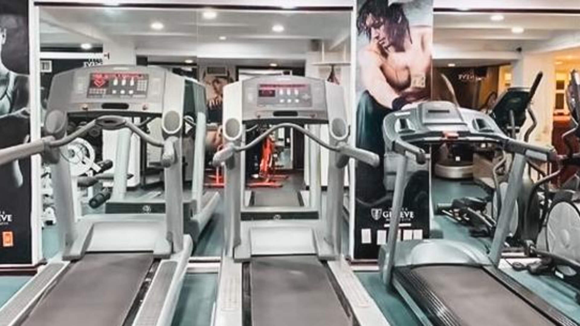 Fitness center equipped with treadmills, elliptical machines, cardio equipment, mirrors, and exercise stations at Hotel Geneve.