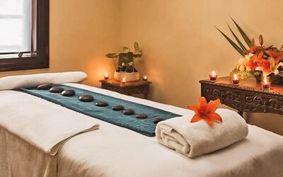 Spa treatment room featuring a massage table, decorative candles, floral arrangements, and a relaxing atmosphere at Hotel Geneve.