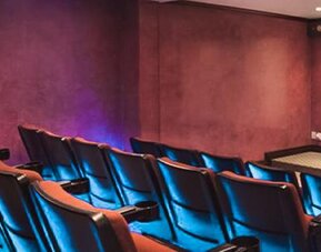 Private theater with tiered seating, blue accent lighting, and a large projection screen at Hotel Geneve.