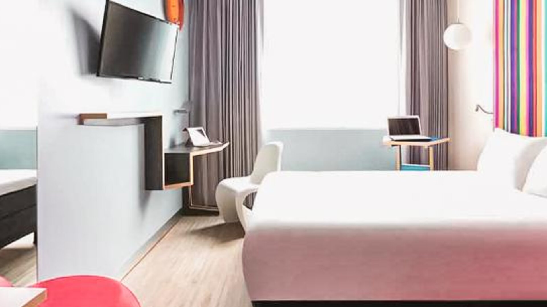 Guest room featuring a bed, workspace, wall-mounted television, contemporary furnishings, and colorful accent walls at Ibis Styles Mexico Reforma.