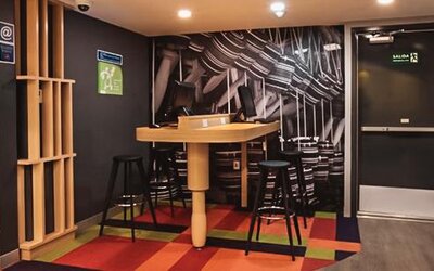 Casual dining area with communal tables, contemporary seating, geometric décor, and an open layout at Ibis Styles Mexico Reforma.