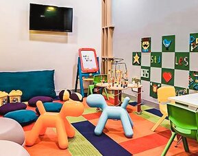Children's play area featuring toys, activity tables, colorful seating, and entertainment options at Ibis Styles Mexico Reforma.