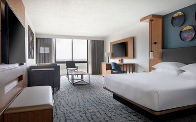 Guest room featuring a king bed, comfortable seating, natural light, and modern amenities at Houston Marriott South at Hobby Airport.