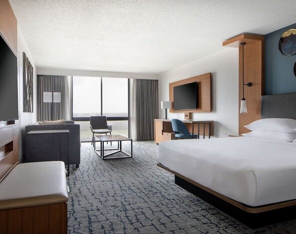 Guest room featuring a king bed, comfortable seating, natural light, and modern amenities at Houston Marriott South at Hobby Airport.