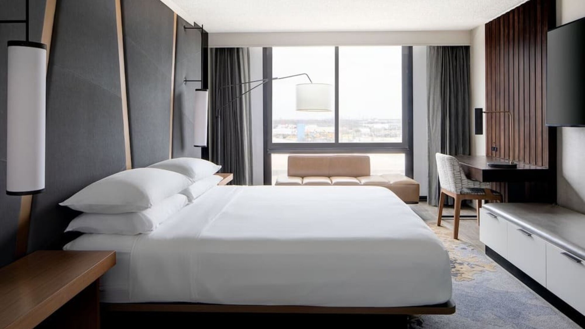 Guest room featuring a king bed, floor-to-ceiling windows, a workspace, and modern décor at Houston Marriott South at Hobby Airport.