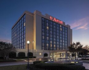 Exterior view showcasing the hotel's contemporary architecture, landscaped grounds, and covered entrance at Houston Marriott South at Hobby Airport.