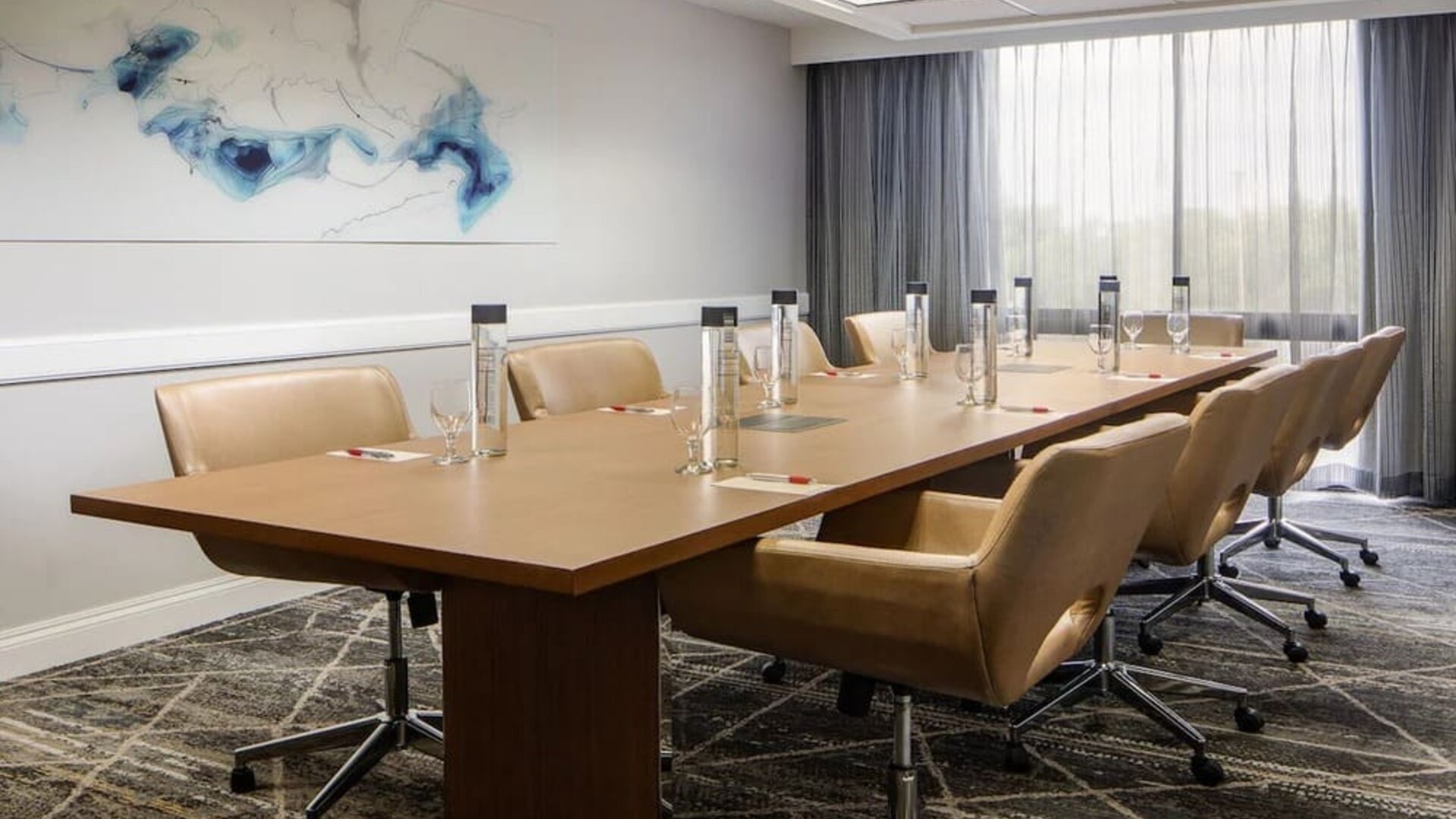 Boardroom featuring a conference table, executive seating, natural light, and presentation amenities for business meetings at Houston Marriott South at Hobby Airport.