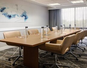 Boardroom featuring a conference table, executive seating, natural light, and presentation amenities for business meetings at Houston Marriott South at Hobby Airport.