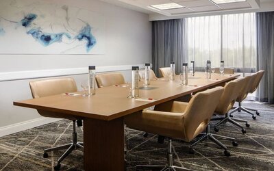 Boardroom featuring a conference table, executive seating, natural light, and presentation amenities for business meetings at Houston Marriott South at Hobby Airport.