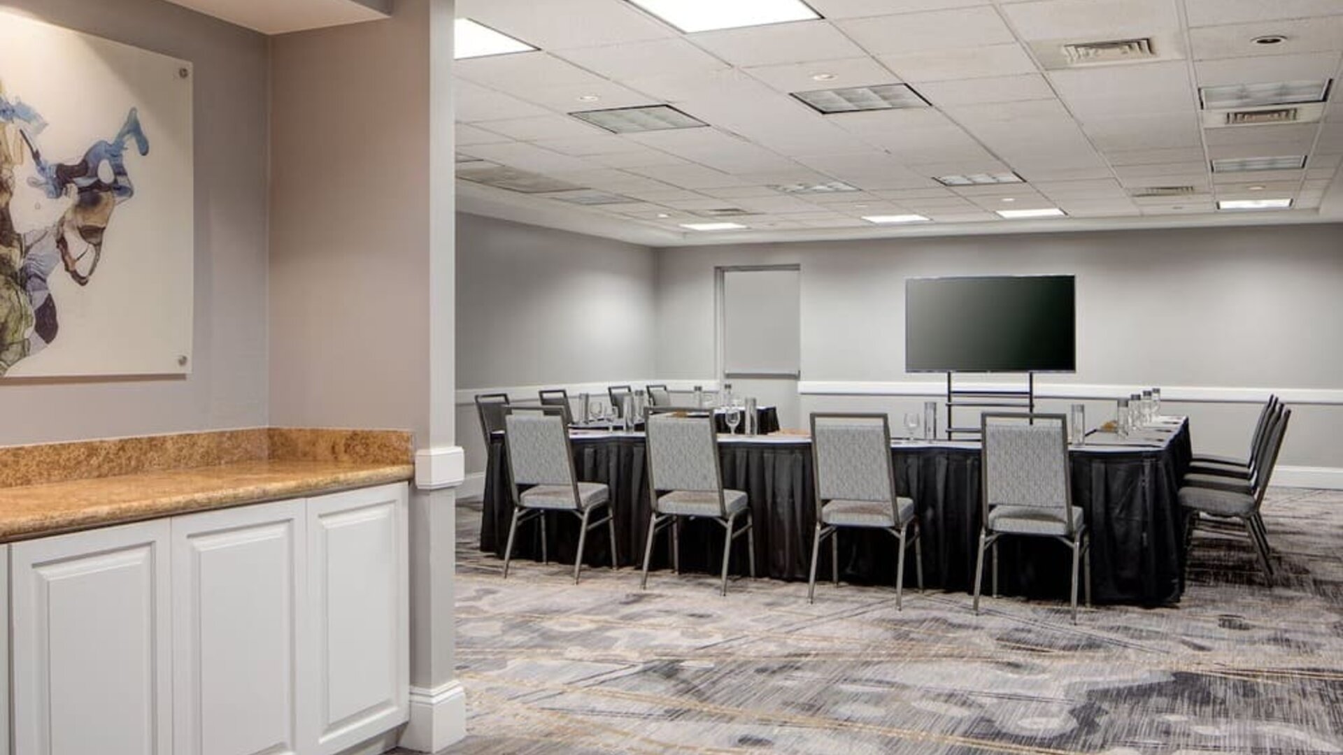 Meeting facility featuring a collaborative seating arrangement, presentation screen, and flexible event space at Houston Marriott South at Hobby Airport.